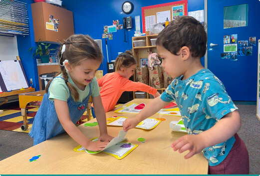 Two children making a craft at a preschool