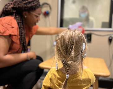 African American woman helping child with hearing game